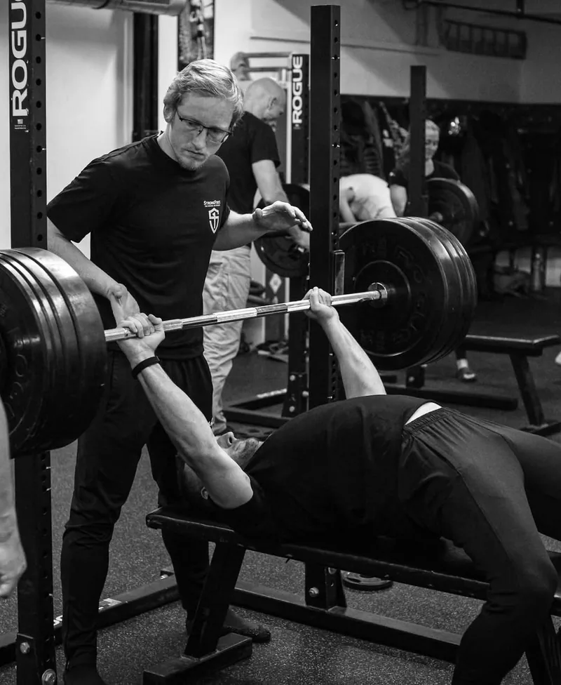Ondra Čech koučuje klienta při bench pressu